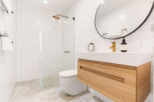 a bathroom with a toilet and a sink and a mirror at Bondi Oasis: 2BR + Balcony Bondi Beach in Sydney