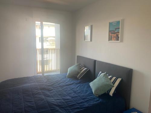 a bedroom with a bed with blue sheets and a window at un endroit de rêve in Marseillan
