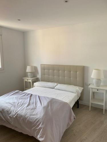 a white bedroom with a large bed and two tables at Apartamento en el centro in Igualada