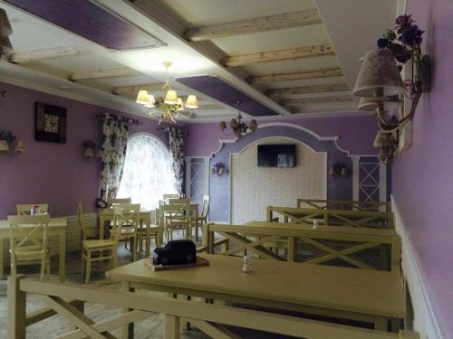 ein Restaurant mit Tischen und Stühlen und ein Zimmer mit lila Wänden in der Unterkunft Polyanskiy Zamok in Poljana