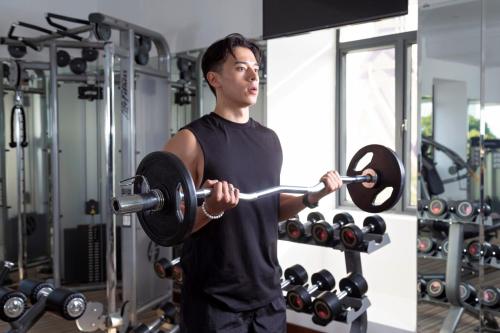 a man lifting a barbell in a gym at Palace Gate Hotel & Resort By EHM in Phnom Penh