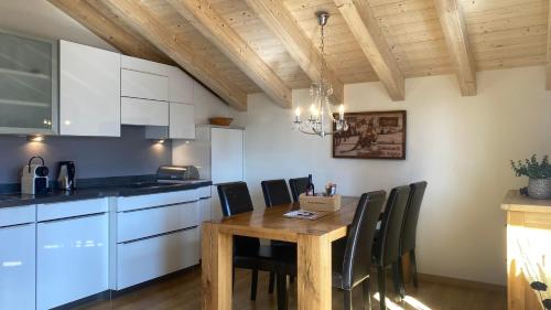 eine Küche mit einem Holztisch und schwarzen Stühlen in der Unterkunft am Bärgbach DG in Bettmeralp