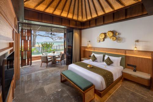 a bedroom with a bed and a dining room with a table at Sumitra Luxury Villas & Resort by Pramana in Sanur