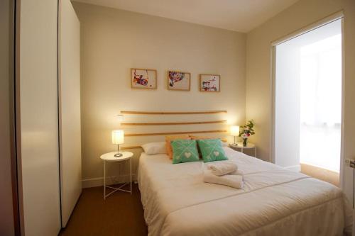 een slaapkamer met een groot wit bed met groene kussens bij La casita de Lola in Santander