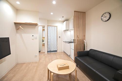 een woonkamer met een zwarte bank en een tafel bij 拾野の家 202和室 in Osaka