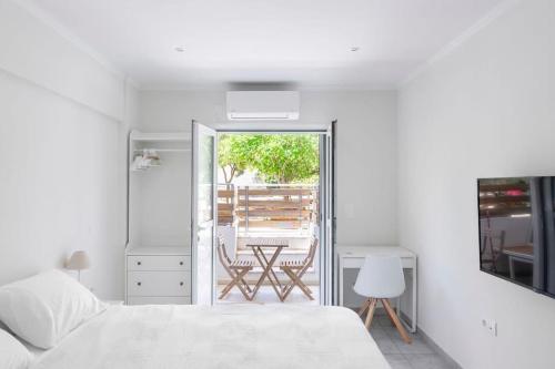 een witte slaapkamer met een bed en een balkon bij Voula's Secret Garden Studio in Athene