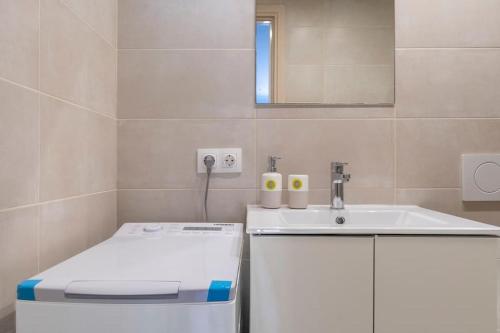 een badkamer met een wastafel, een toilet en een spiegel bij Voula's Secret Garden Studio in Athene