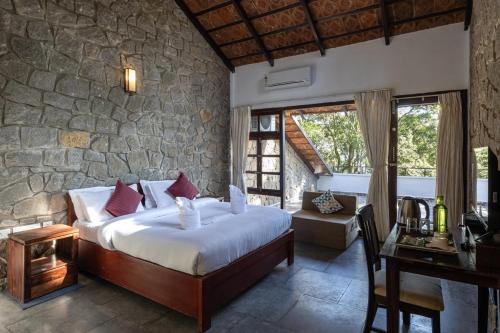 a bedroom with a bed and a stone wall at Avadale Munnar (Stag Groups Not Allowed) in Chinnakanal