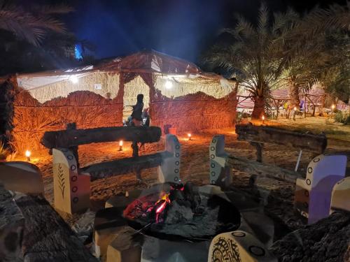 una persona sentada junto al fuego en una yurta por la noche en Desert Escape siwa -with palm & olive Garden - Hot Spring, en Siwa