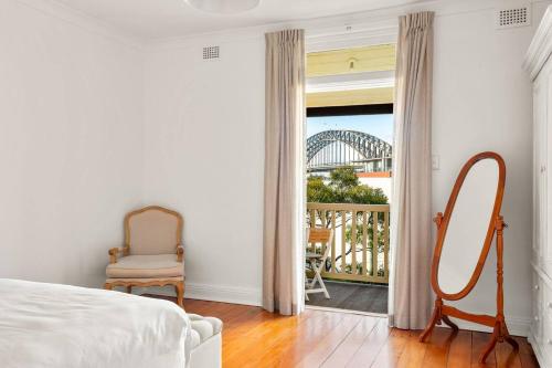 een slaapkamer met een bed, een spiegel en een raam bij Contemporary Charm with Spectacular Harbour Views in Sydney