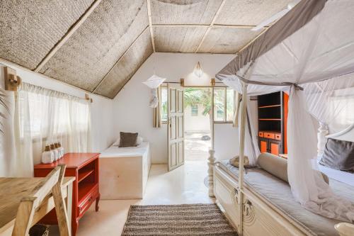 a bedroom with a bed and a desk and a table at Cinnamon Hotel in Jambiani