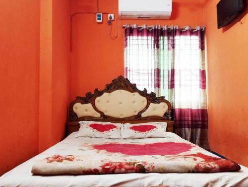 ein Schlafzimmer mit einem Bett mit einer orangefarbenen Wand in der Unterkunft Hotel Al-Hayat Abasik in Dhaka