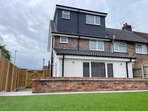 een huis met een stenen muur en een hek bij Gable House in Crewe