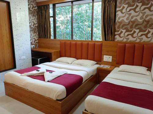 two beds in a room with windows at Hotel airport annex in Mumbai
