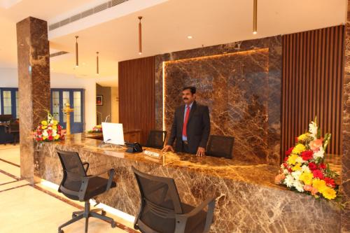 a man standing at a reception desk in a lobby at National Park Residency Kottayam in Ettumānūr