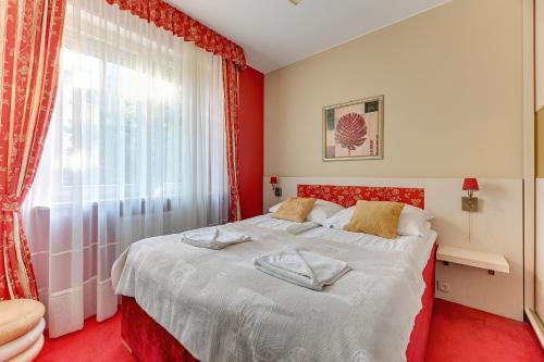 a red bedroom with a bed with towels on it at Grand Apartments - Patio Mare Apartments in Sopot