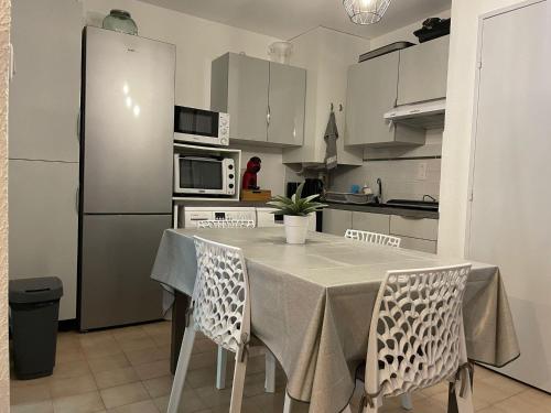 une cuisine avec une table avec des chaises et un réfrigérateur dans l'établissement Appartement T2 46m2 avec grande terrasse, à Sanary-sur-Mer