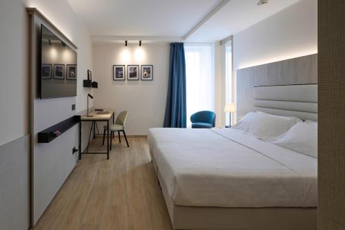 Habitación de hotel con cama y escritorio en RMH Modena Raffaello en Módena