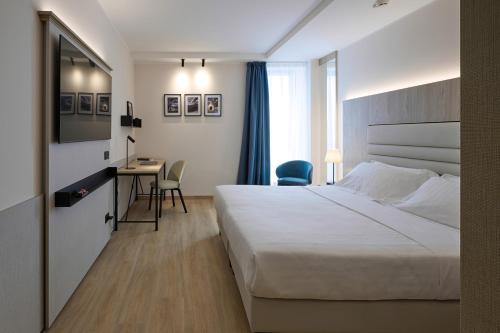 Habitación de hotel con cama y escritorio en RMH Modena Raffaello, en Módena