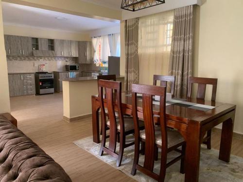 a kitchen and dining room with a wooden table and chairs at Happy home from home in Kitengela 