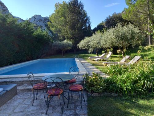 een patio met een tafel en stoelen naast een zwembad bij La roulotte du petit paradis in Saint-Rémy-de-Provence