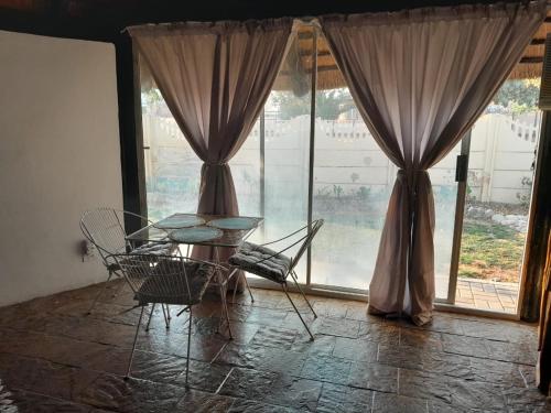 einen Tisch und Stühle in einem Zimmer mit Fenstern in der Unterkunft The Lapa Apartment in Gobabis
