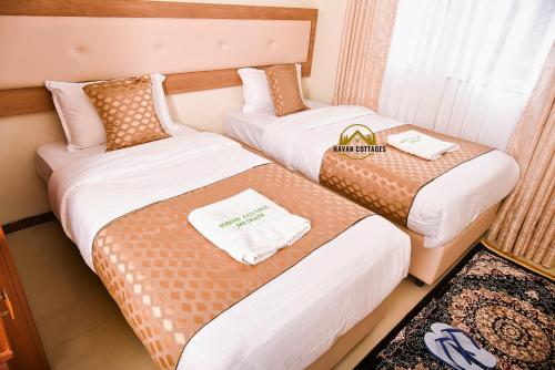 two beds in a hotel room with towels on them at Havan Furnished Apartment-Milimani N9 in Nakuru