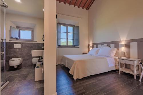 a bedroom with a white bed and a bathroom at Podere La Doccia in Civitella in Val di Chiana
