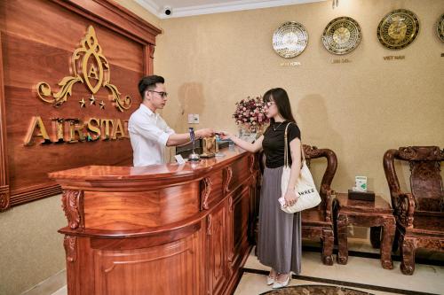 胡志明市的住宿－Air Star Hotel，站在酒吧的男人和女人