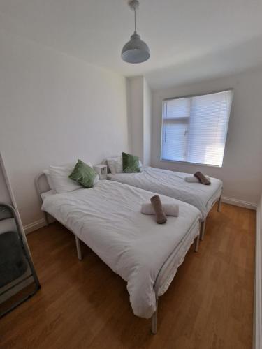 two beds in a white room with a window at 3 mins from the theme park! Charming Bedford Hideaway! in Kempston