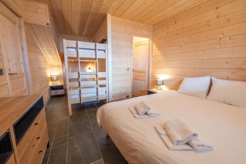 a bedroom with a bed in a wooden cabin at Beau chalet GUSTAVE 4 chambres 50m piste Huez Express in LʼHuez