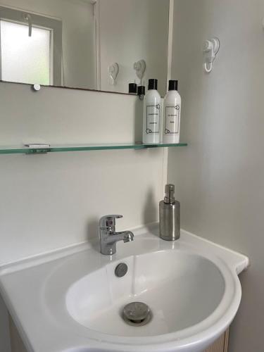 un lavabo blanc dans une salle de bain avec un miroir dans l'établissement Chez Roger - Bungalow climatisé avec TV - 2 chambres 4 personnes, à Boofzheim