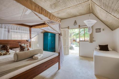 a bedroom with a canopy bed and a bathroom at Cinnamon Hotel in Jambiani