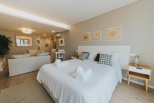 um quarto com uma grande cama branca e um sofá em Studio Marina by Madeira Best Apartments no Funchal