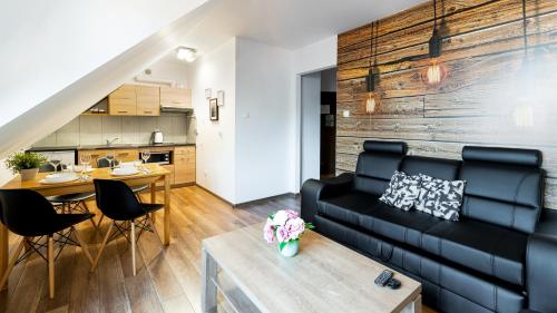 a living room with a black couch and a table at Apartamenty Sun & Snow Leśny Dom in Karpacz