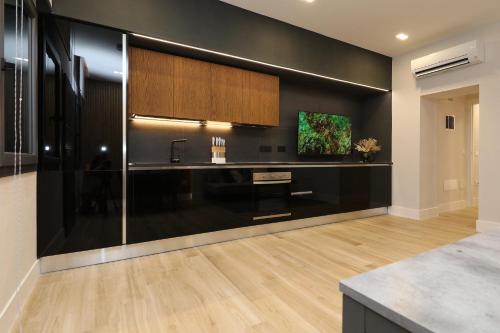 uma cozinha com paredes pretas, um lavatório e uma televisão em Best price vs quality-Fully equipped & renovated 2Room Suite MonteNero-City Centre em Olbia