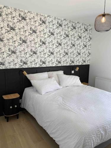 a bedroom with a white bed with a black and white wall at Gîte le 9 bis Kervadail in Baden
