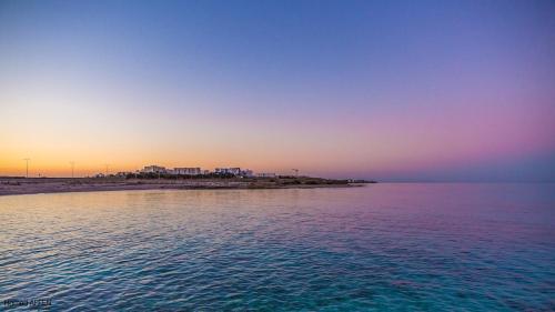 a sunset over the ocean with a beach in the background at Maison Eline in Harqalah
