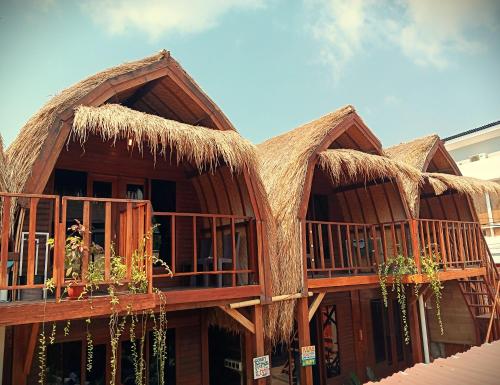 un edificio con techos de paja y plantas en los balcones en Good Vibes Bungalows, en Gili Trawangan