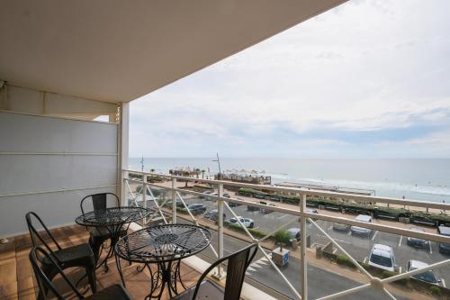d'un balcon avec des tables et des chaises et une vue sur l'océan. dans l'établissement Appartement - vue exceptionnelle, à Lacanau-Océan
