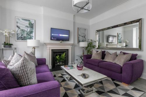 un salon avec des canapés violets et une télévision dans l'établissement Luxury 1BR Broadstairs: 2 mins walk to the beach, à Kent