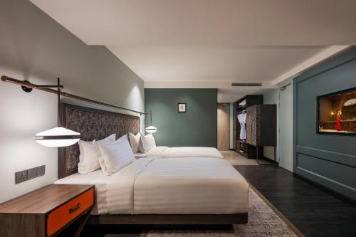 a bedroom with a large white bed and a desk at The George Penang by The Crest Collection in George Town