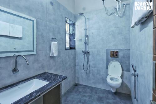 La salle de bains est pourvue de toilettes, d'un lavabo et d'une douche. dans l'établissement StayVista at Riverfront Cottage, à Jabalpur
