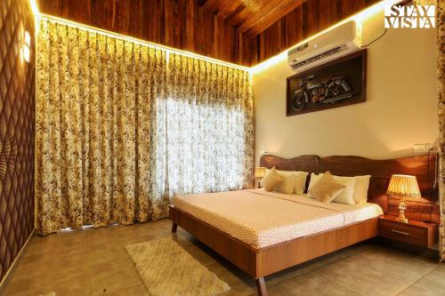 a bedroom with a bed and a large window at StayVista at Riverfront Cottage in Jabalpur