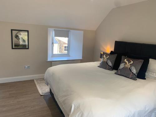 een slaapkamer met een groot wit bed met kussens en een raam bij The Carthouse (Luxury 2 bed with private hot tub) in Newburgh