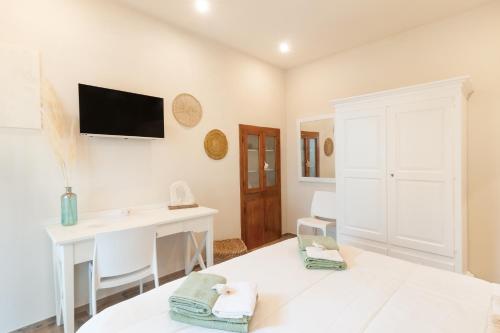 Dieses weiße Zimmer verfügt über einen Schreibtisch und einen TV an der Wand. in der Unterkunft Il Piccolo Borgo - con vista in Certaldo