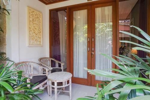 a porch with two chairs and a wooden door at Wayan Homestay Sanur in Sanur