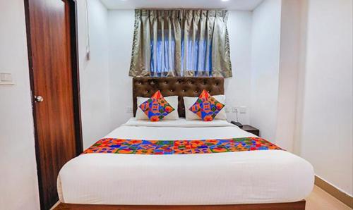 um quarto com uma grande cama branca com almofadas coloridas em FabHotel Earth 2, Chennai em Chennai