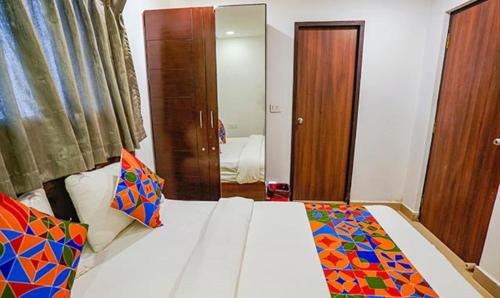 a bedroom with a white bed with colorful pillows at FabHotel Earth - Nr Guindy Industrial Estate in Chennai