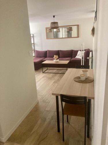 ein Wohnzimmer mit einem Tisch und einem lila Sofa in der Unterkunft Studio dans un parc verdoyant in Andrézieux-Bouthéon